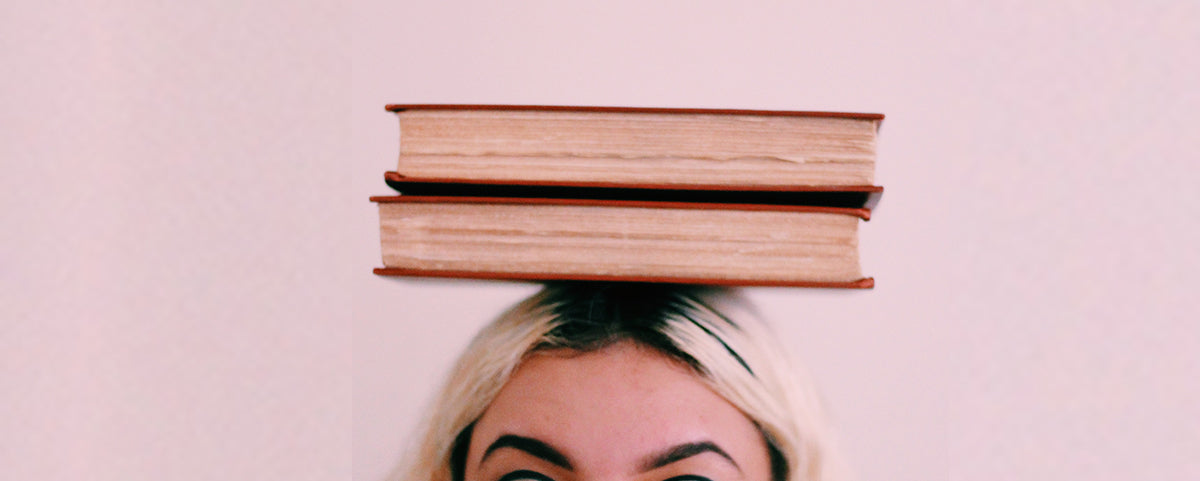 A woman balancing a stack of books on her head.